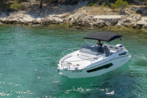 boat karnic sl702 on the crystal clear waters, with black tent on it, and island in the behind