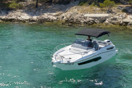 boat karnic sl702 on the crystal clear waters, with black tent on it, and island in the behind
